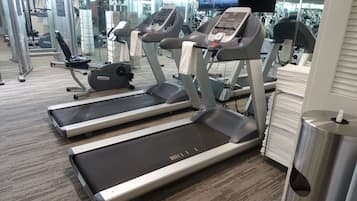 A gym with treadmills, weight machines, and a mirror wall.