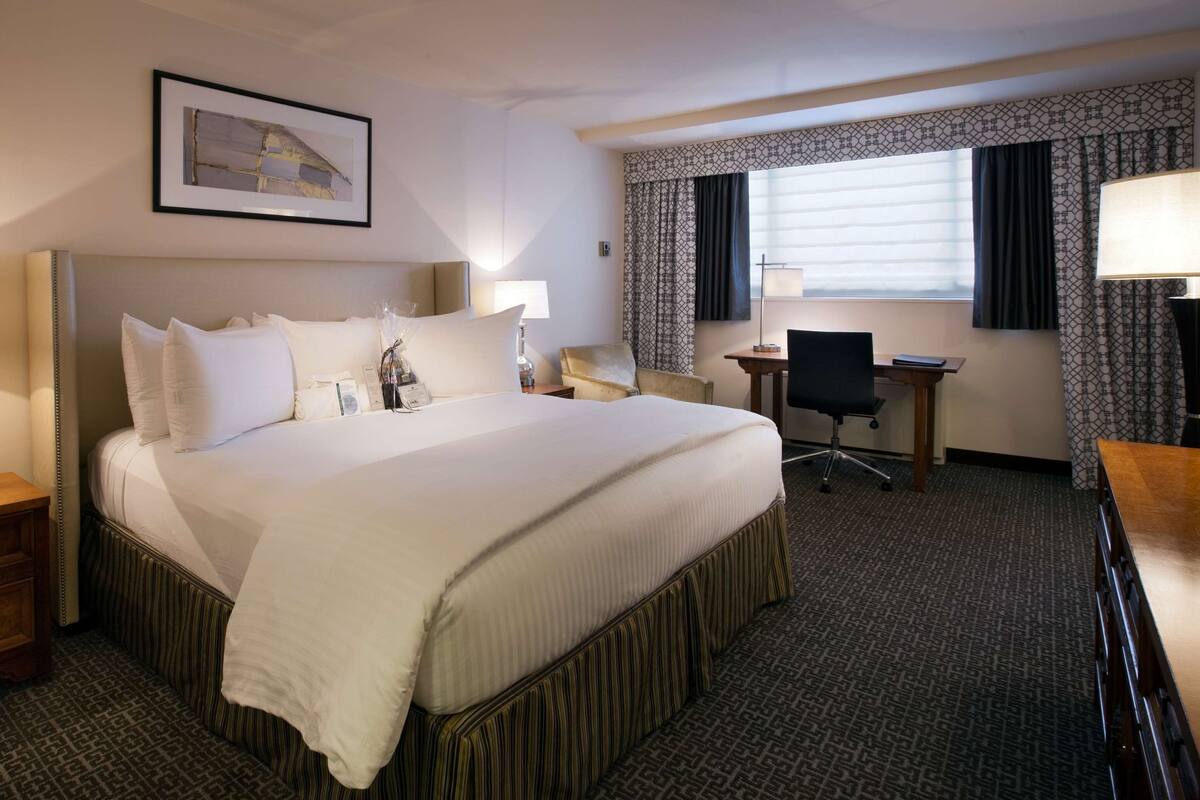 A hotel room with a large bed, bedside tables, a desk, and a chair.