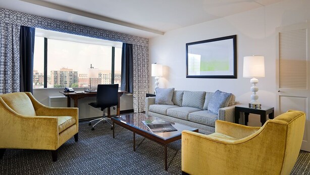 A hotel room with a sofa, two armchairs, a coffee table, a desk, and a lamp. - State Plaza Hotel (Washington)