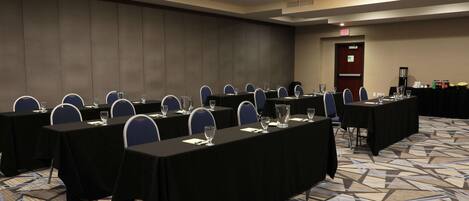 A conference room with tables set for meetings, equipped with chairs and glassware.
