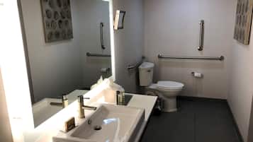 Een moderne badkamer met een groot wastafel, toilet en handgrepen.