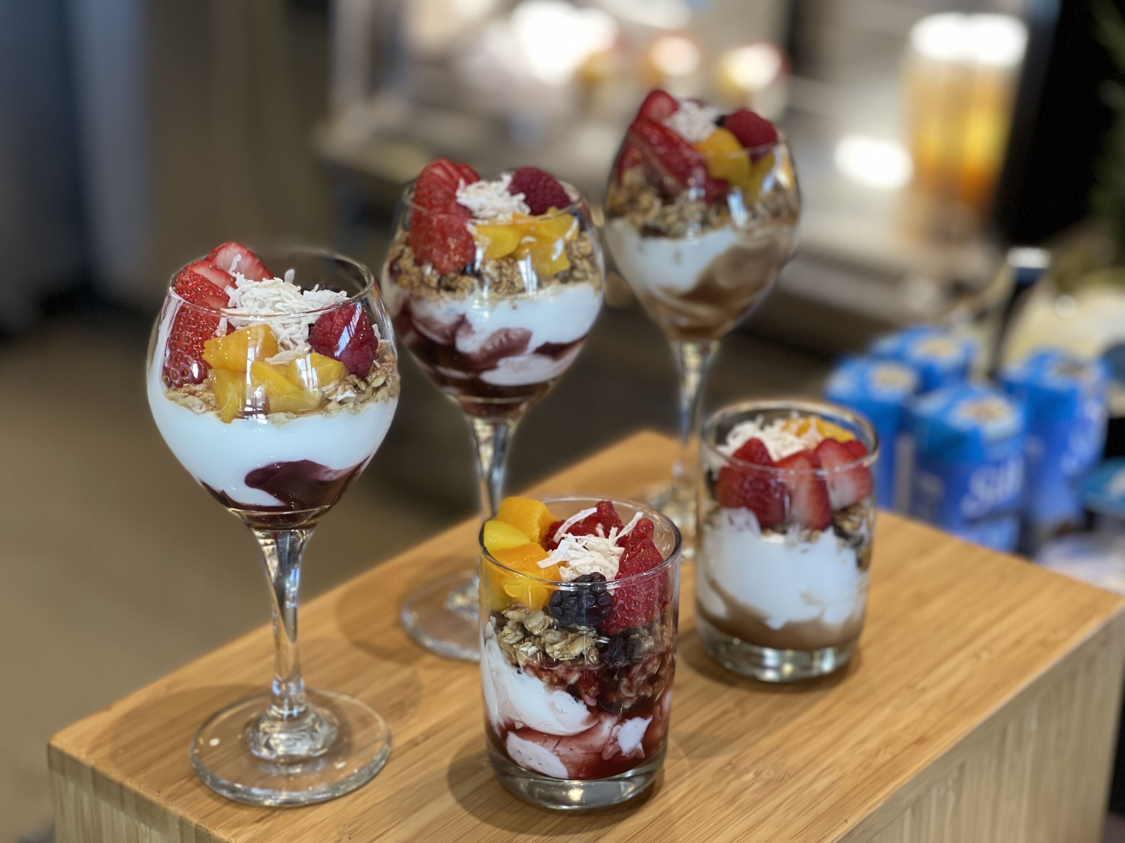 Four dessert glasses on a wooden table.