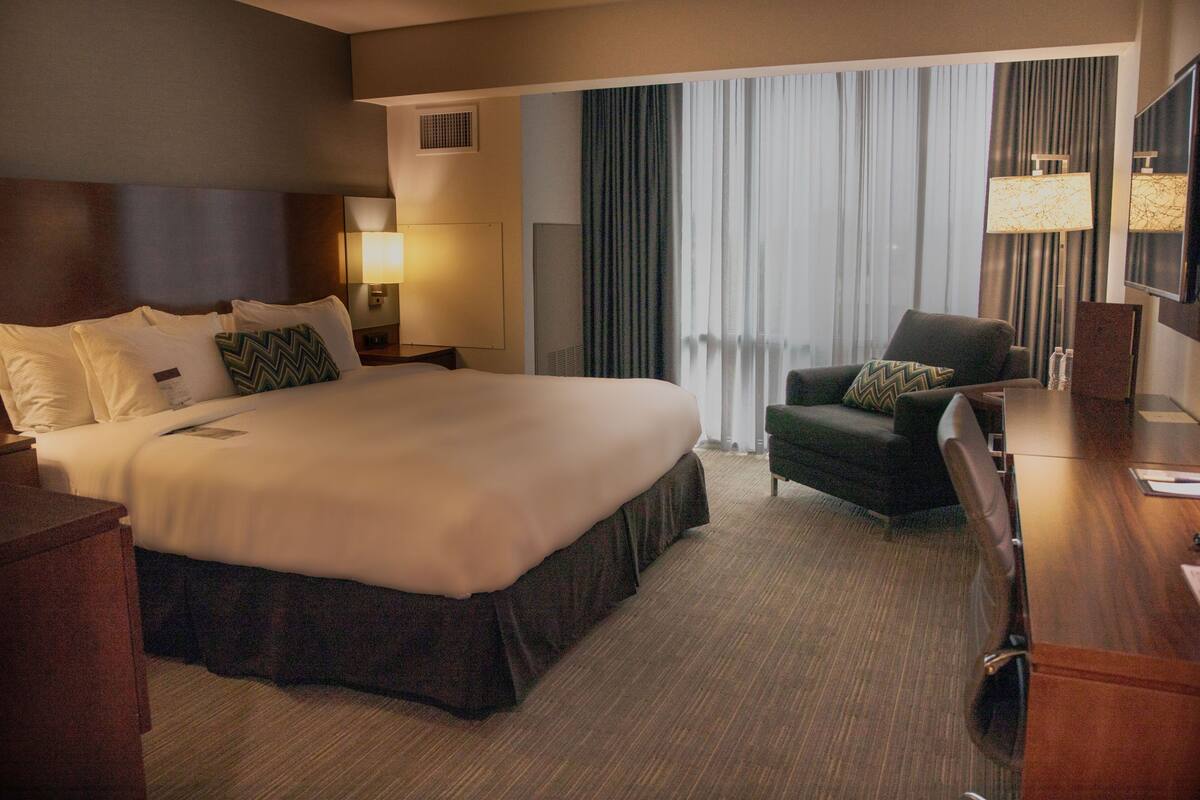 Een hotelkamer met een groot bed, een bureau, een stoel en een televisie.