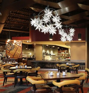 Un restaurant doté de nombreuses tables et chaises, d’un bar et de luminaires décoratifs suspendus au plafond.