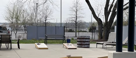 Un espacio al aire libre con bancos y mesas, rodeado por una valla y árboles.