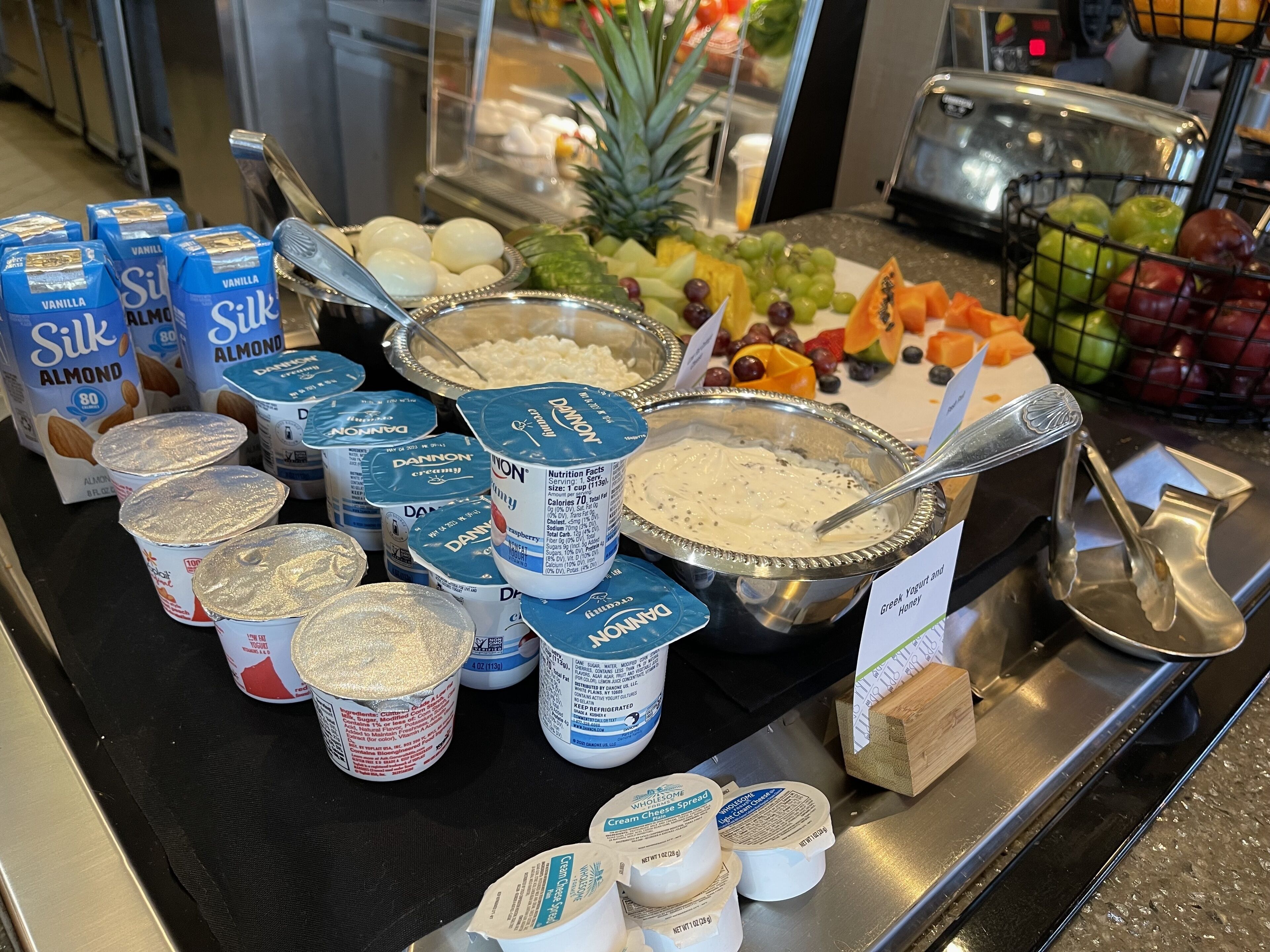 A buffet with various food items including yogurt, cheese spread, and fruits.