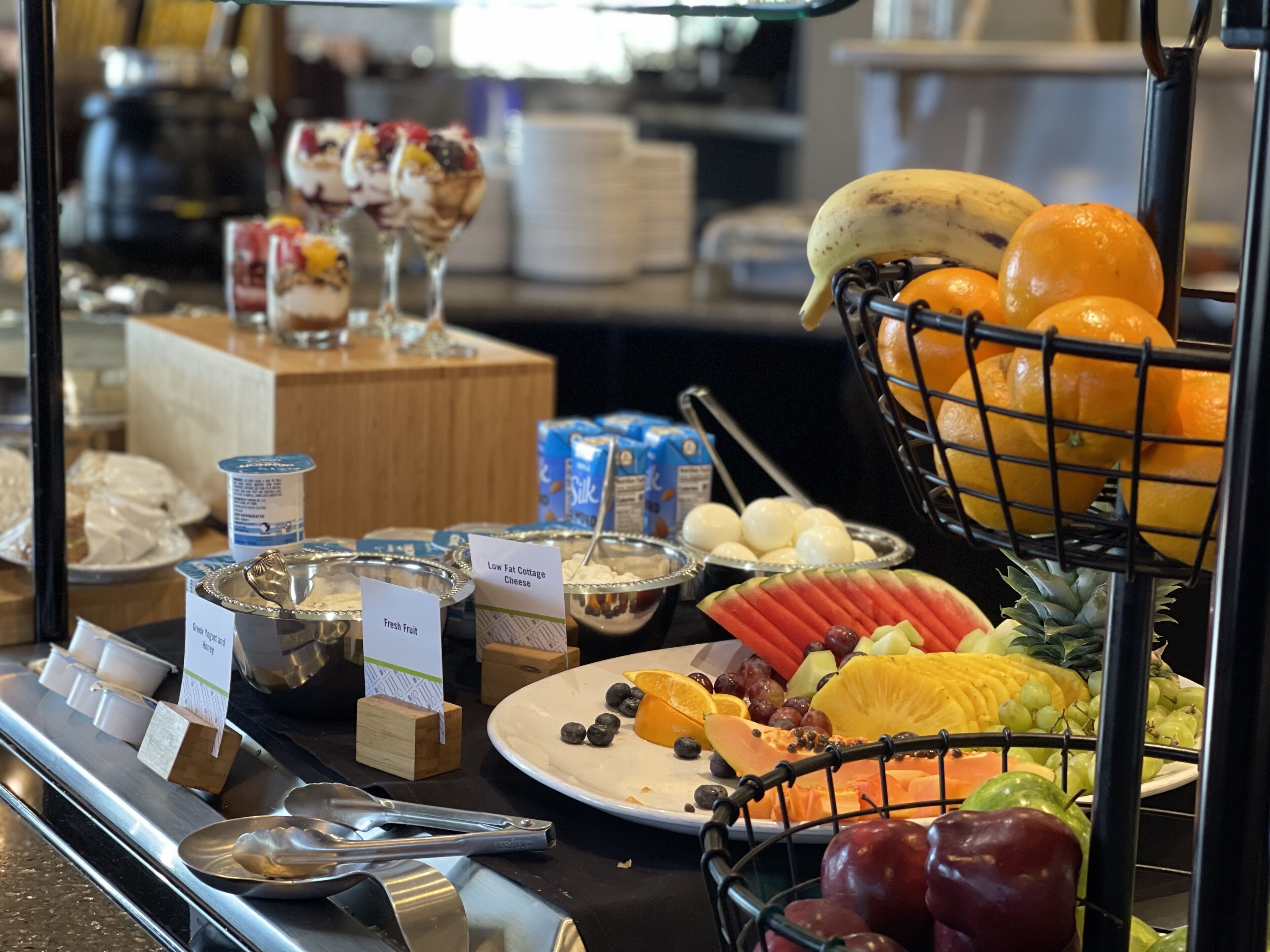 Un bufé con diversas opciones de comida, incluyendo frutas, quesos y postres.