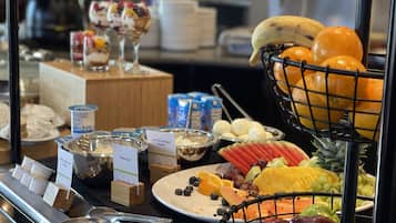 Un bufé con diversas opciones de comida, incluyendo frutas, quesos y postres.