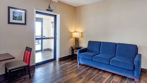 A room with a blue sofa, a chair, a small table, a lamp, and an exit sign. - Comfort Inn Rockford near Casino District (Rockford)