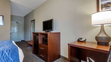 A hotel room with a bed, a desk with a lamp, a television, and a phone.