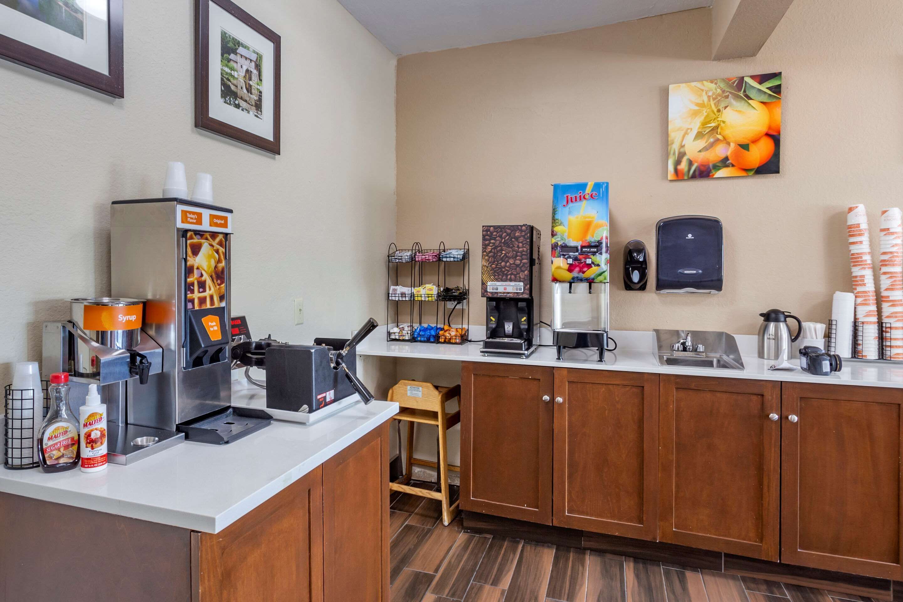 A hotel kitchen with a coffee machine, a juice dispenser, and a coffee maker.