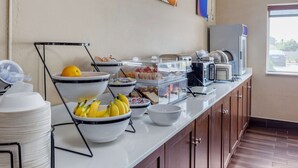 A buffet setup with various food items, including fruits and pastries, and a microwave. - Comfort Inn Rockford near Casino District (Rockford)