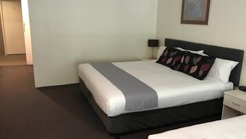 A hotel room with a large bed, a nightstand, a lamp, and a painting on the wall.