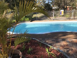 Una piscina al aire libre, sillones reclinables de piscina