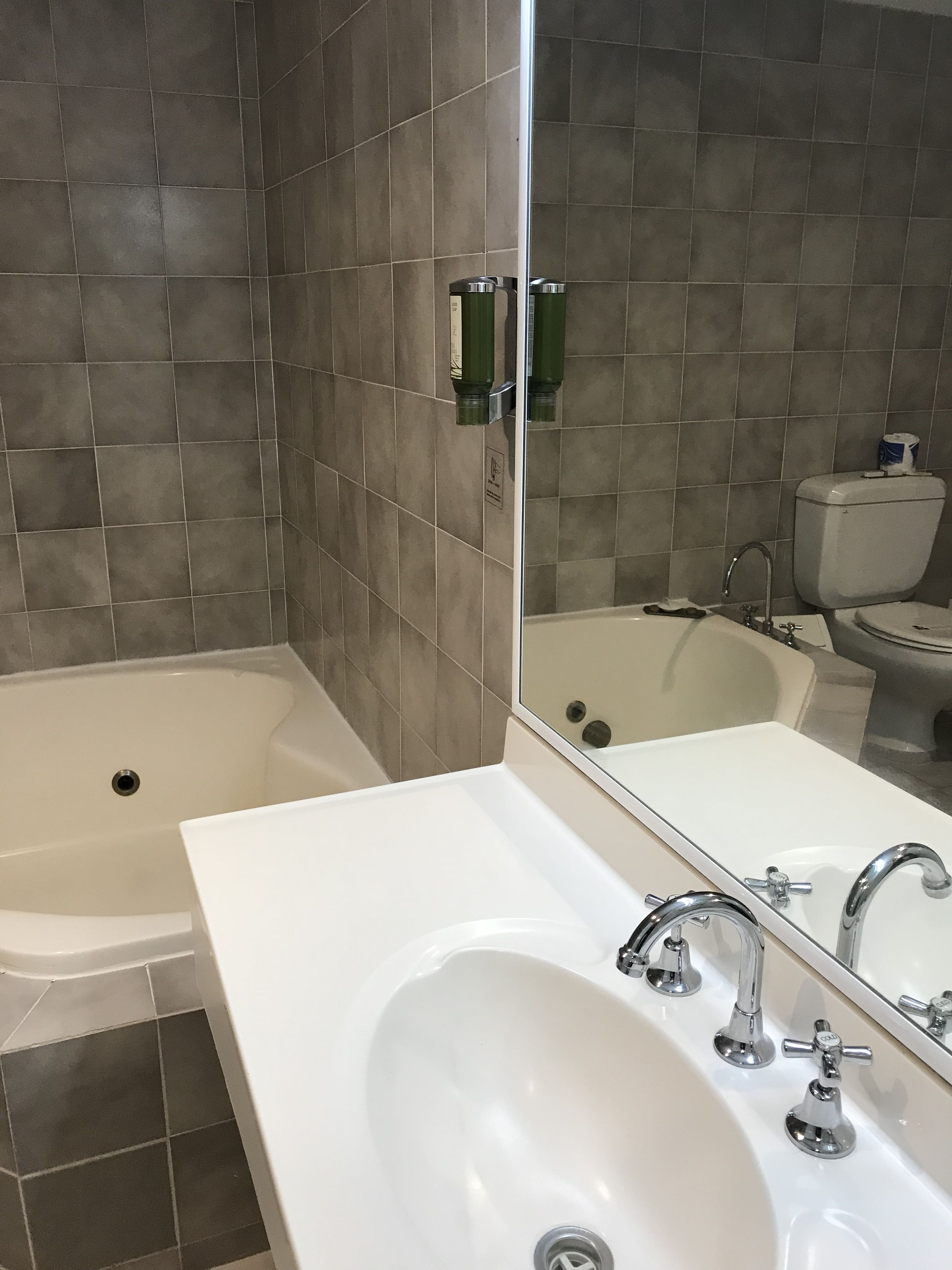 Ein Badezimmer mit einer Badewanne, einem Waschbecken mit Spiegel und einer Toilette.