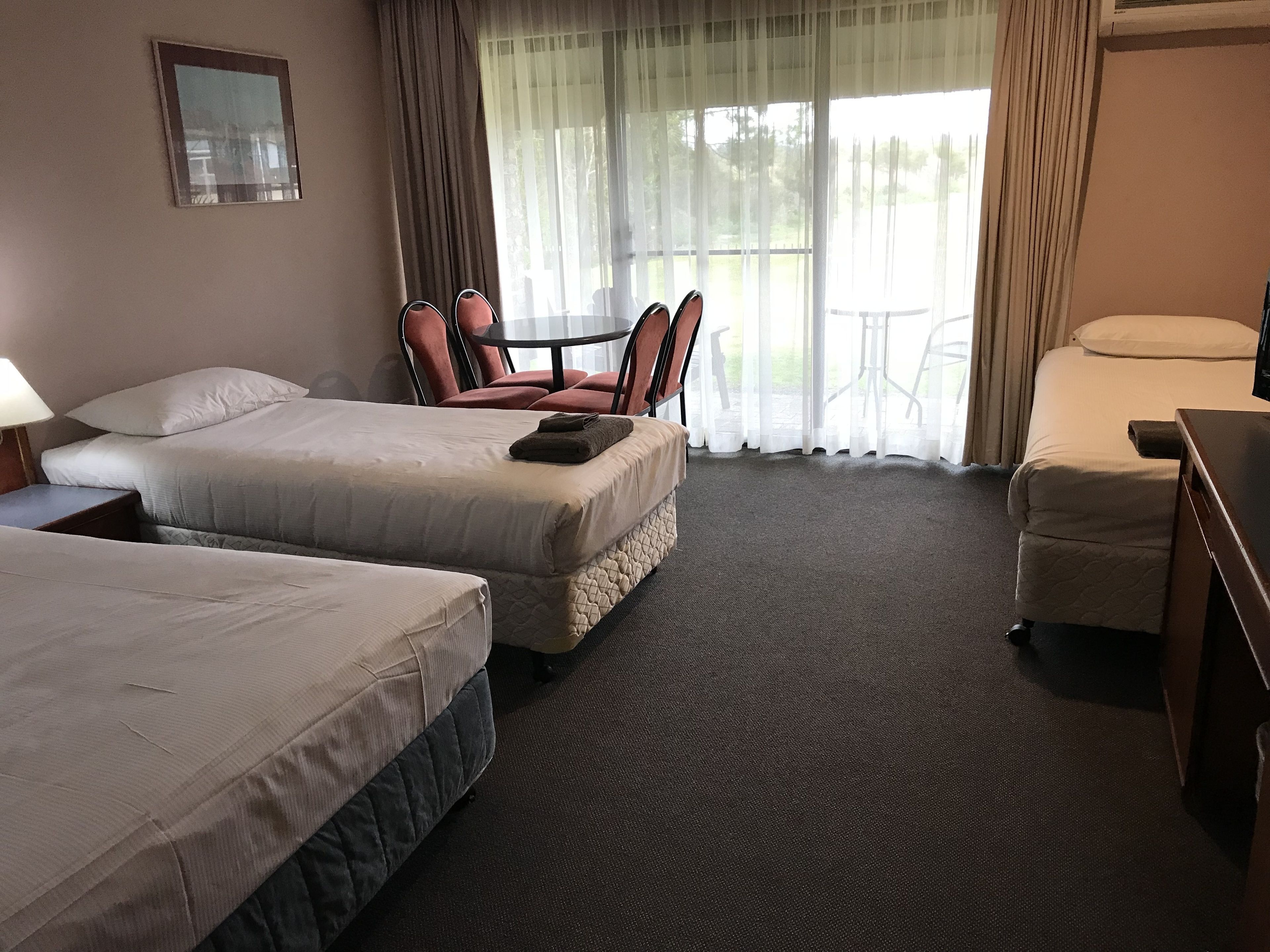 Een hotelkamer met twee bedden, een bureau, een stoel en een tafel.