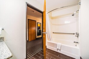 A bathroom with a bathtub, shower, and a door leading to another room.