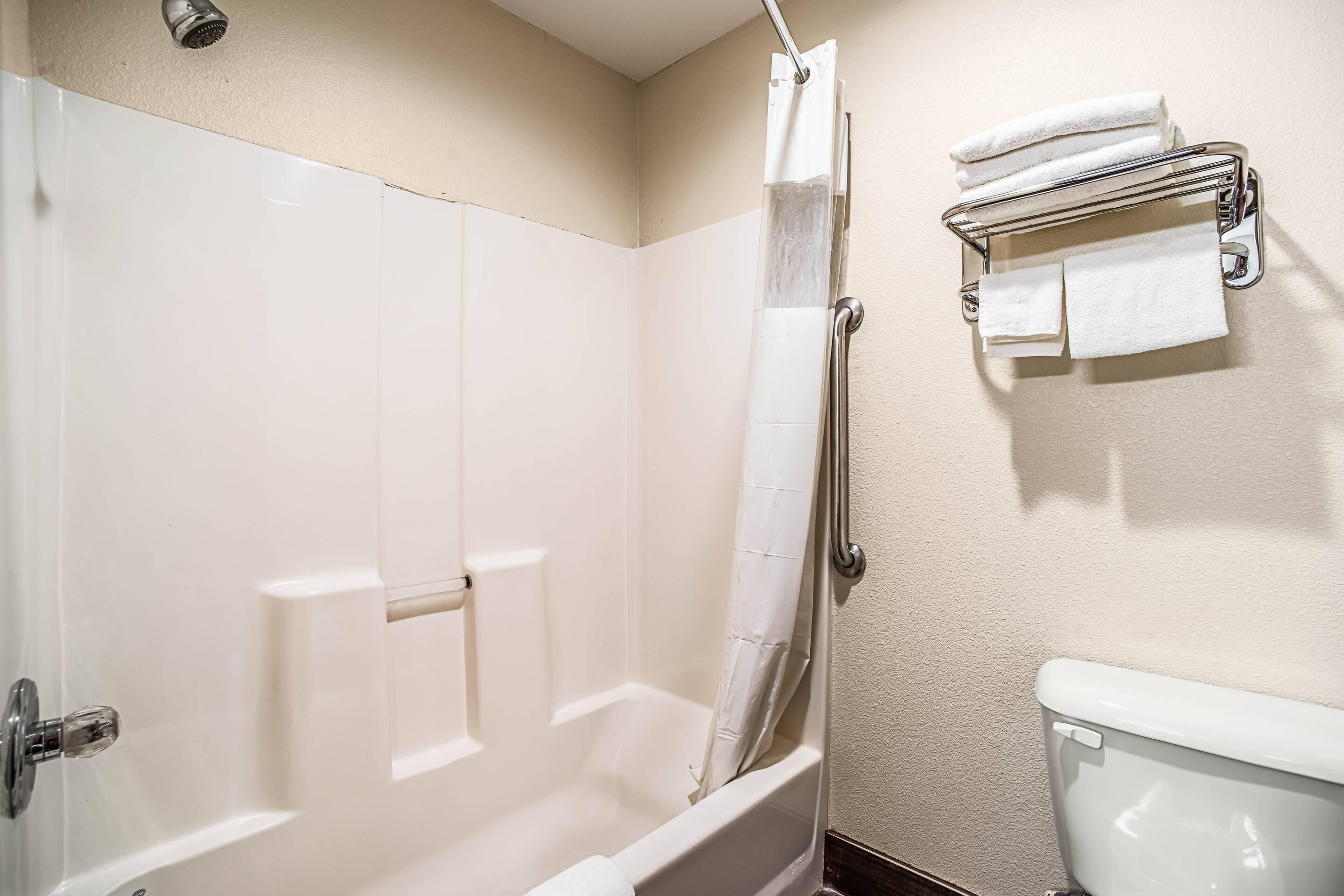 A bathroom with a bathtub, a toilet, and a towel rack.