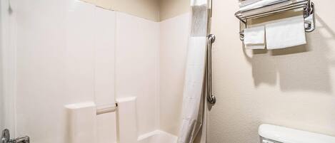A bathroom with a bathtub, a toilet, and a towel rack.
