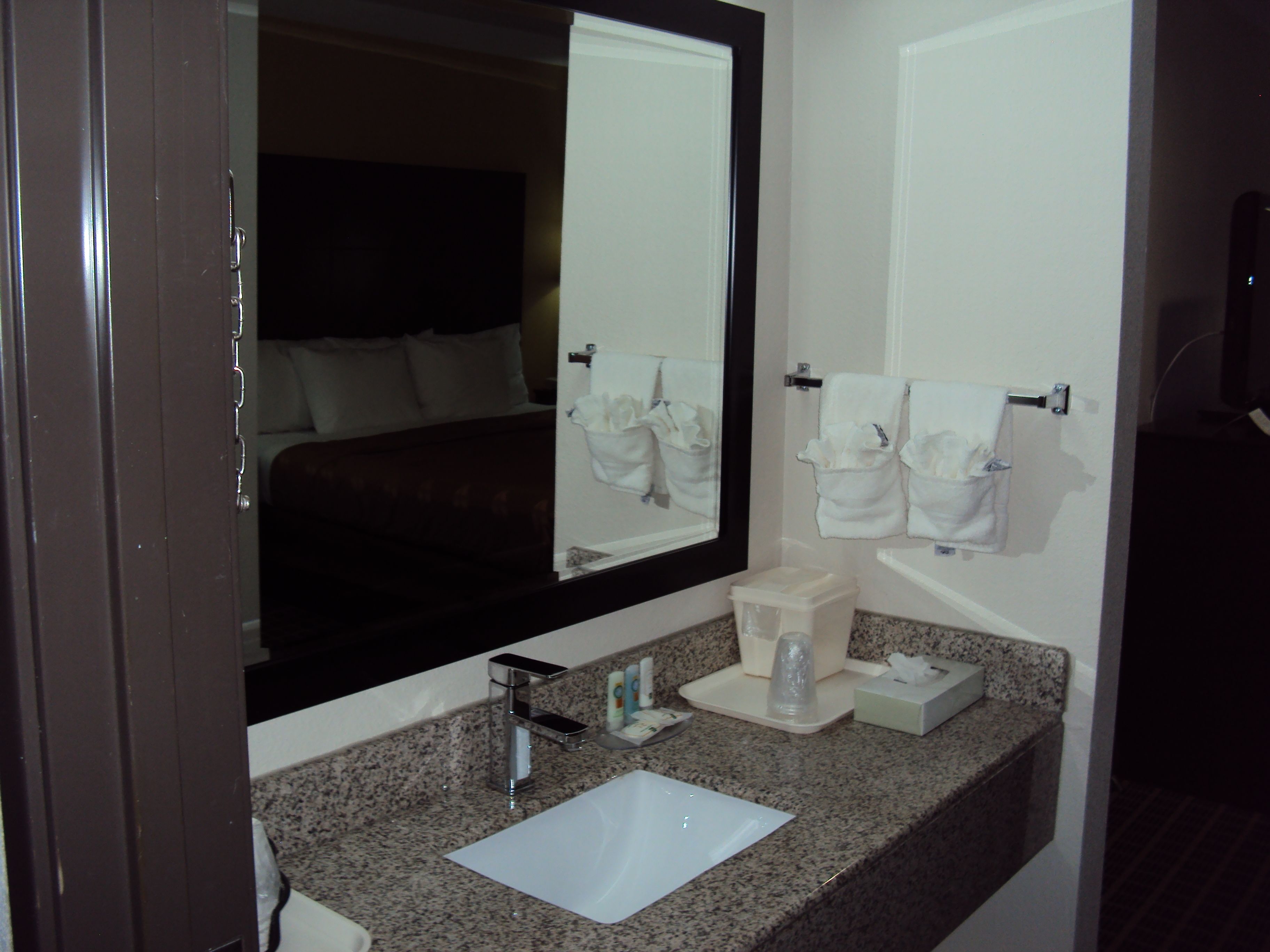 A hotel bathroom with a sink, mirror, and towel racks.