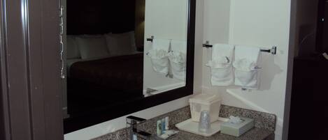 A hotel bathroom with a sink, mirror, and towel racks.