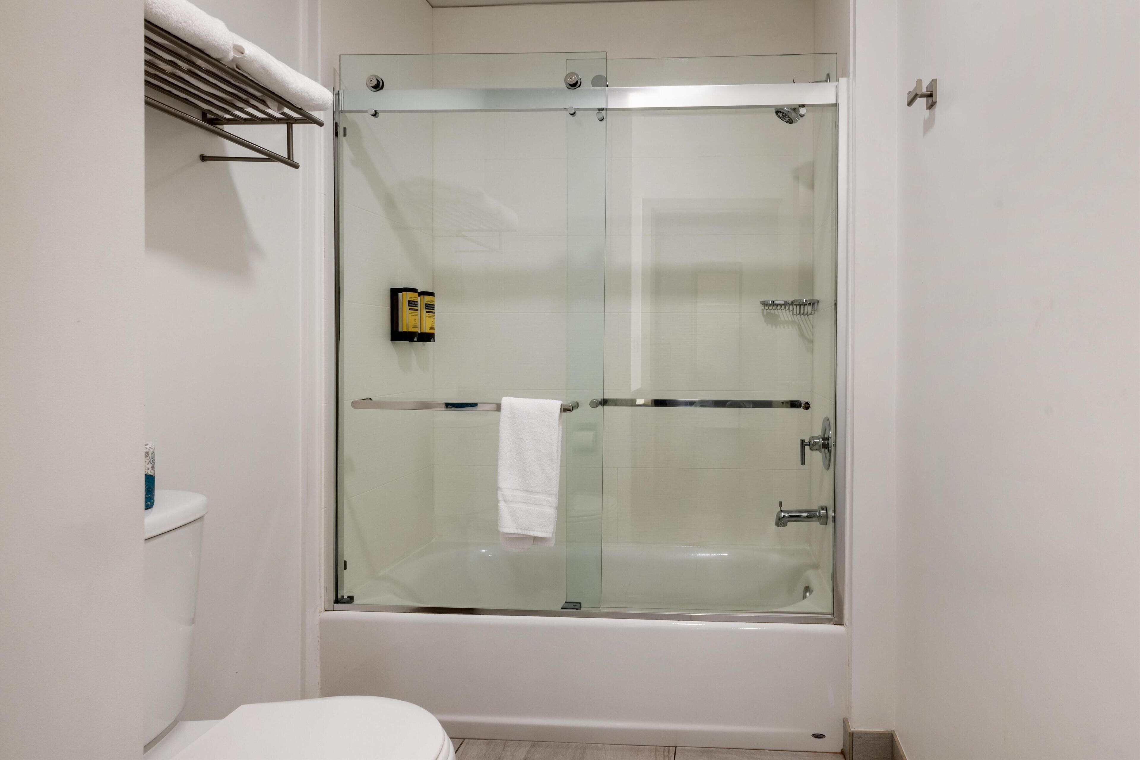 A modern bathroom with a glass-enclosed shower, a white toilet, and a towel rack.
