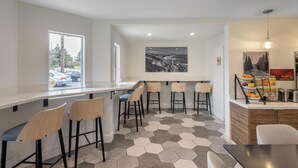 A modern kitchen with a hexagonal tile floor, a bar area with stools, and a large window offering a view of the outside. - Best Western Plus Executive Suites (Redwood City)