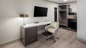 A modern bedroom with a desk, chair, TV, and built-in closet. - Best Western Plus Executive Suites (Redwood City)