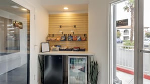 A compact kitchenette with a refrigerator, a small freezer, and a shelf with snacks. - Best Western Plus Executive Suites (Redwood City)