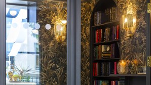A cozy reading nook with a green sofa, a bookshelf, and a patterned floor. - The Academy - Small Luxury Hotels of the World (London)