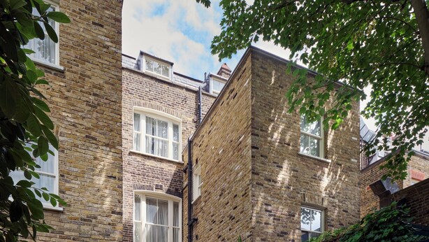 A brick house with a covered patio area featuring outdoor furniture and a variety of plants. - The Academy - Small Luxury Hotels of the World (London)