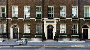 A traditional brick building with a black door and windows, a bicycle parked in front, and a sign that reads "The Academy". - The Academy - Small Luxury Hotels of the World (London)