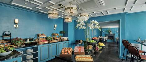 A modern kitchen with blue walls, a marble countertop, and a variety of food items and utensils.