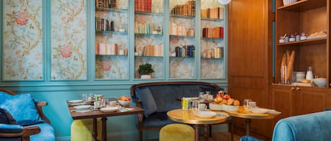 A cozy dining area with a wooden table set for two, surrounded by blue upholstered chairs.