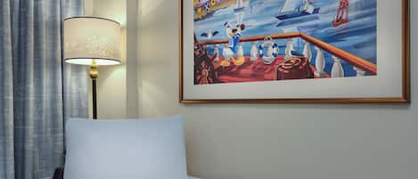 Ein Hotelzimmer mit einem Bett, einer Lampe und einem gerahmten Gemälde, das ein Meerbild zeigt.