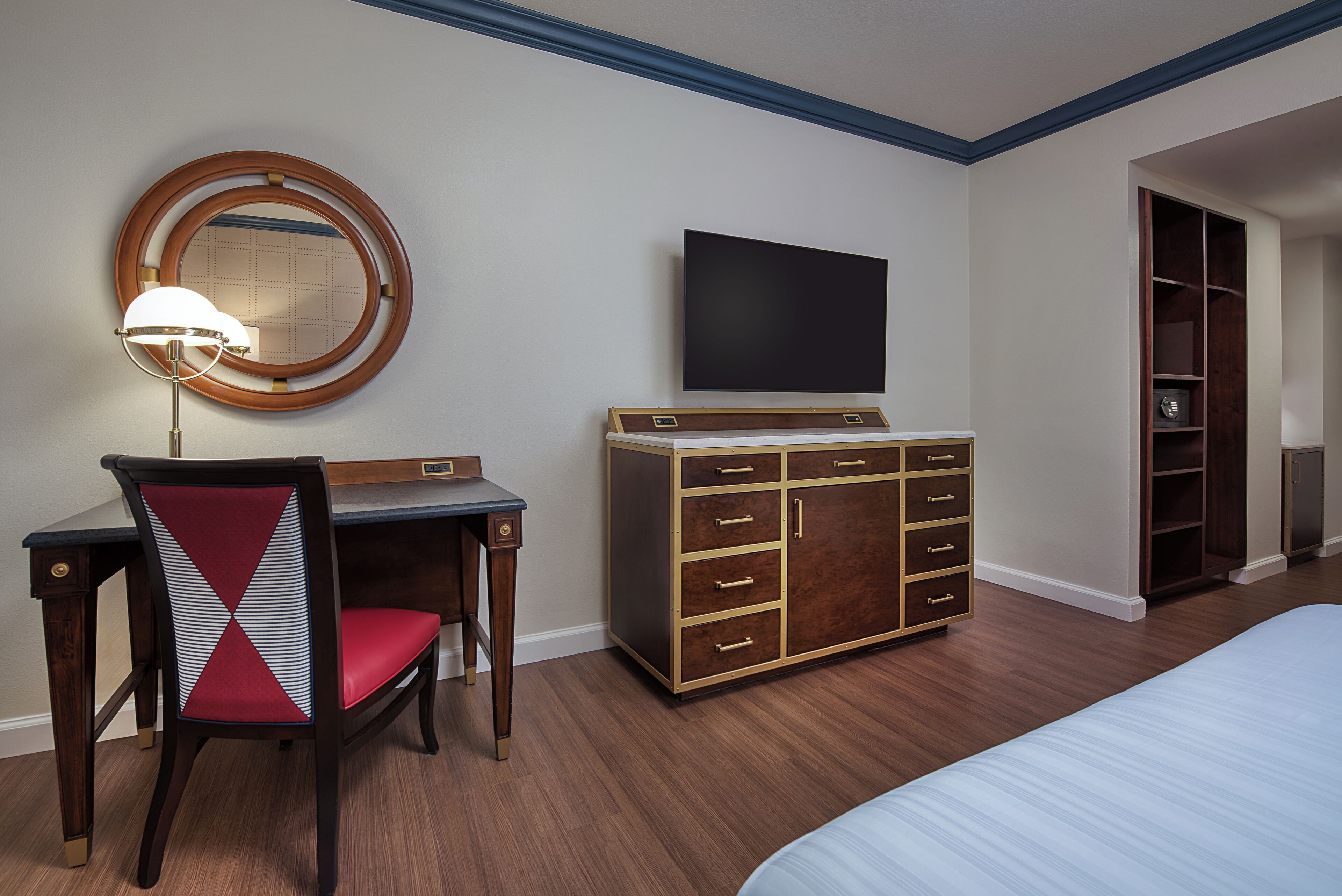 Ein Hotelzimmer mit einem Bett, einem Schreibtisch mit Stuhl, einem Fernseher und einem Kleiderschrank.