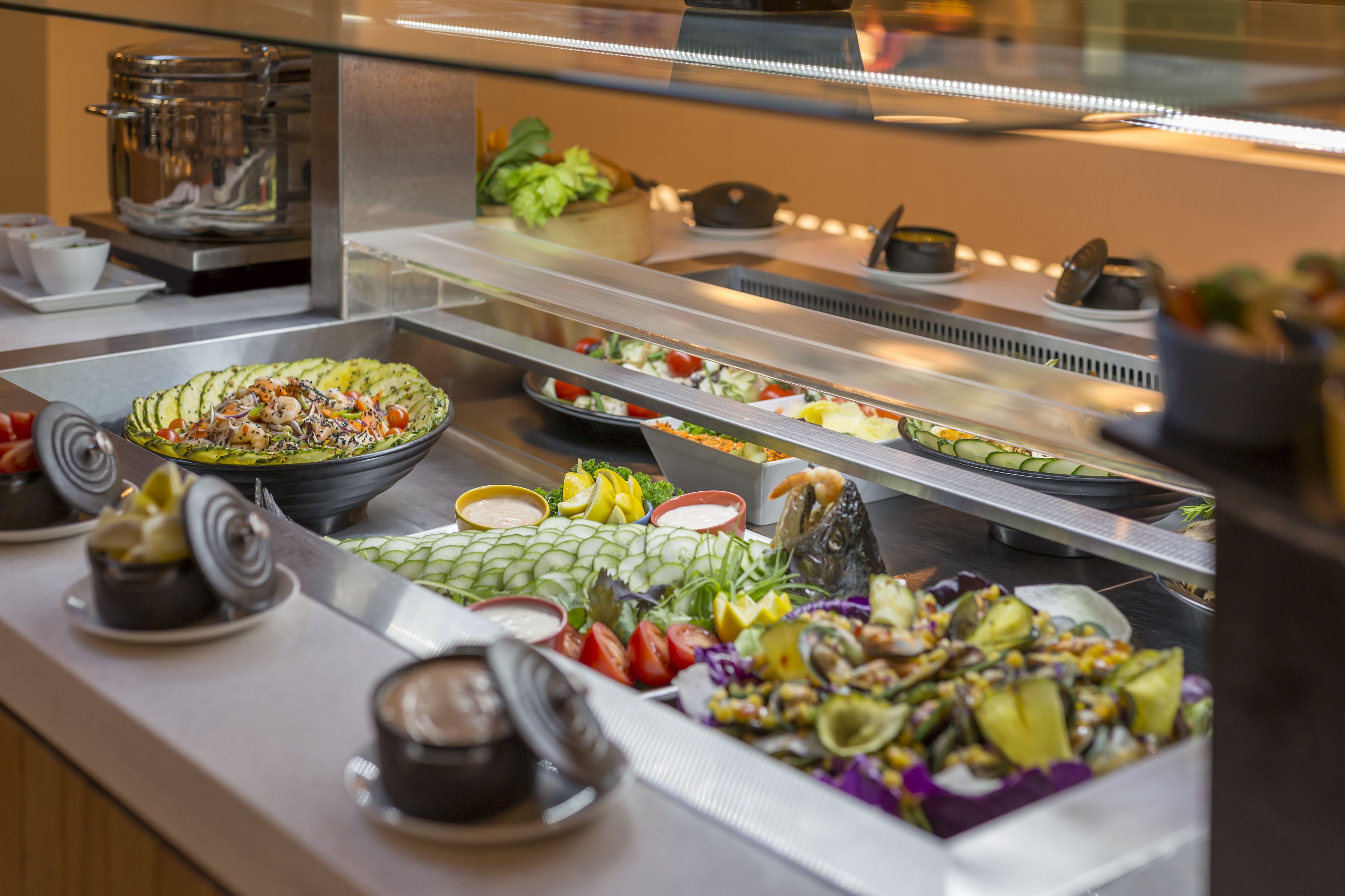 Un bufé con diversos platos, entre ellos ensaladas, verduras y mariscos.