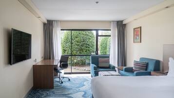 Una habitación de hotel con cama, escritorio, silla, sofá y televisor.