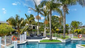 A swimming pool with lounge chairs and palm trees. - Holiday Inn Auckland Airport by IHG (Auckland)