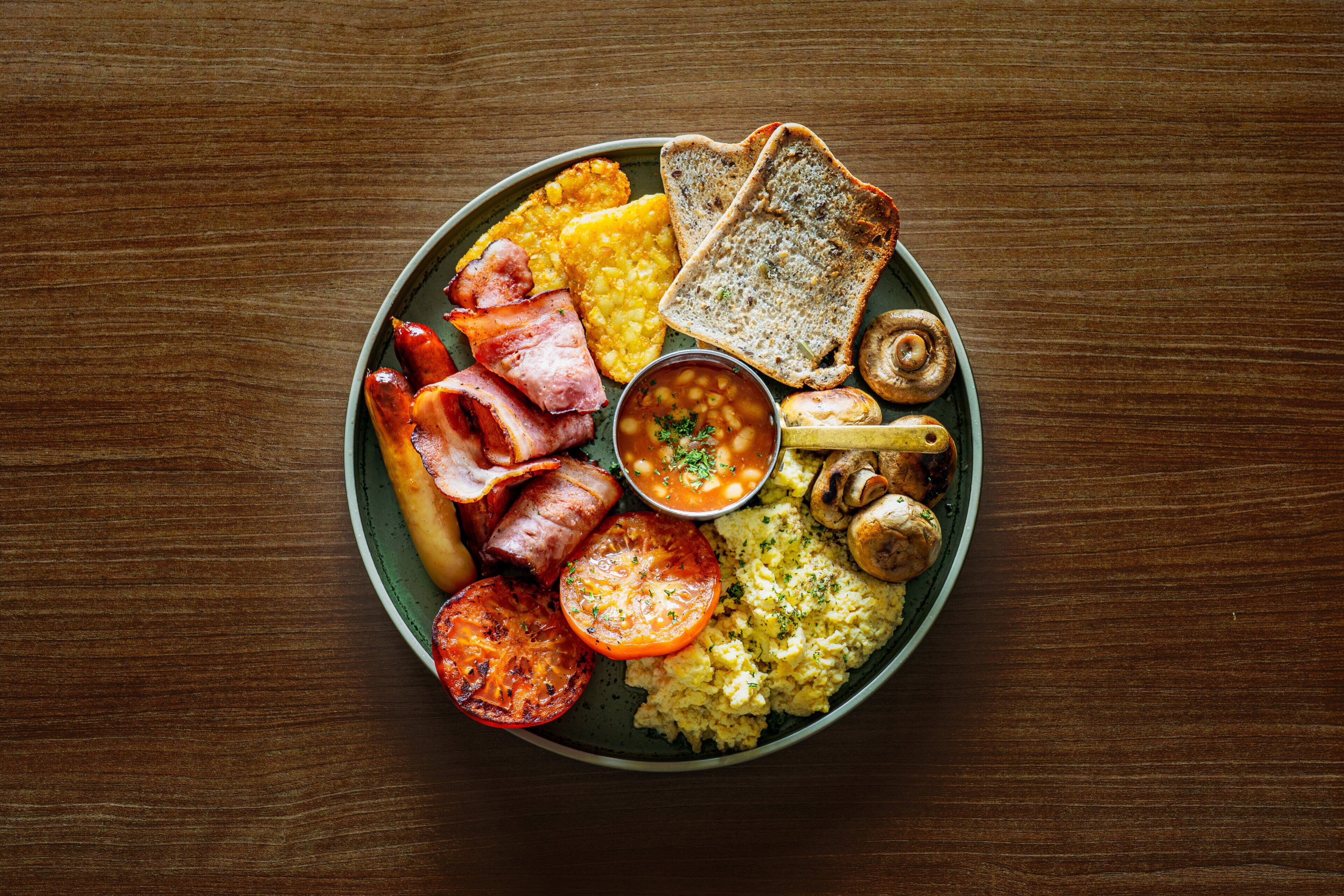 Un plato de comida para el desayuno con huevos, tocino, tostadas y frijoles.