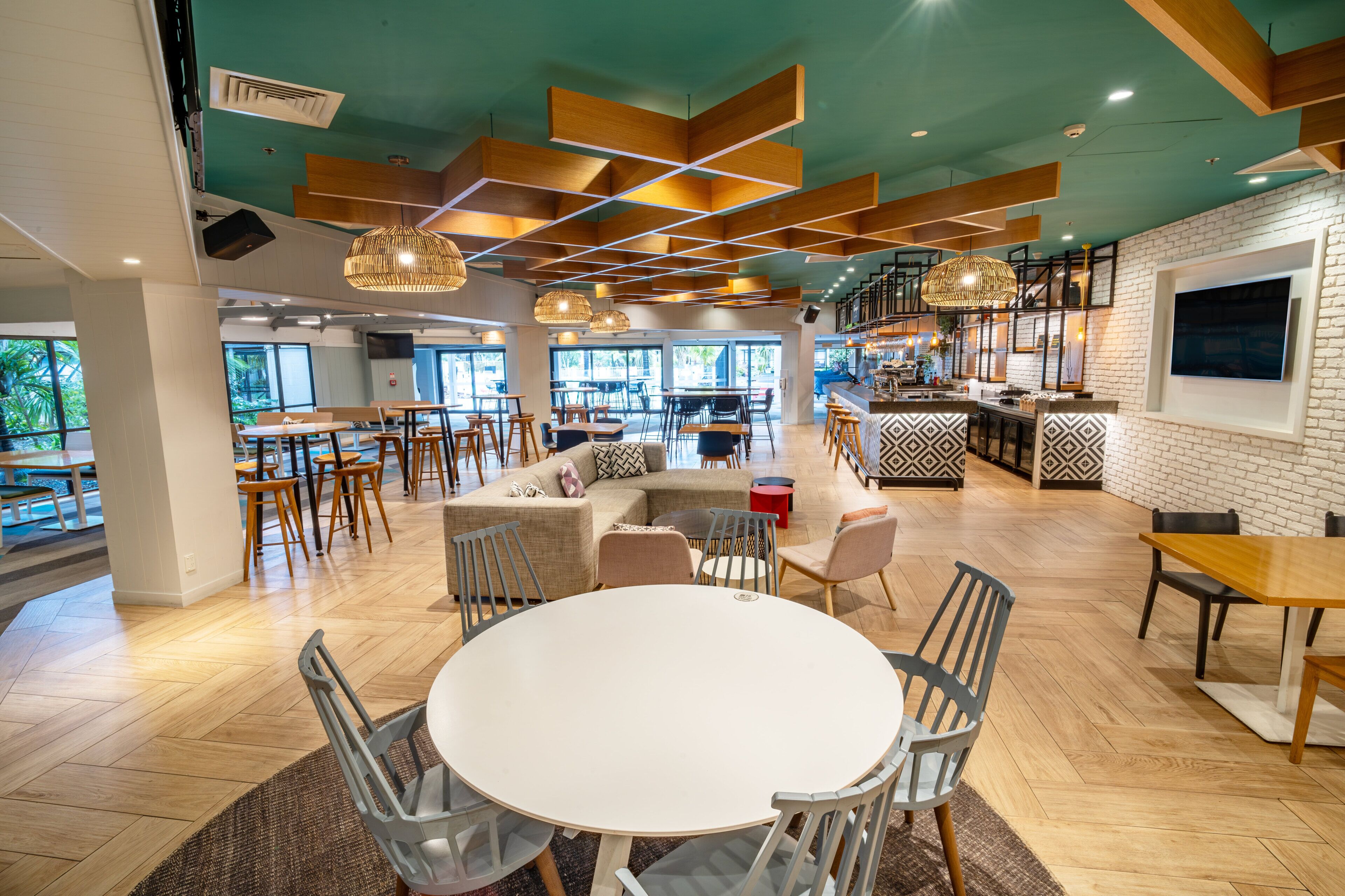 A modern interior with a central round table, multiple seating areas, and a kitchen area.