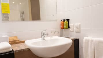 A bathroom with a white sink, a mirror, and toiletries on the wall.
