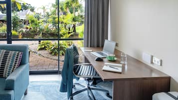 Une chambre d’hôtel moderne dotée d’une grande fenêtre, d’un bureau avec un ordinateur portable, d’une chaise et d’un canapé.
