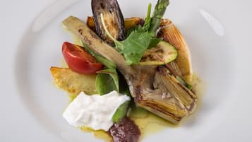 Un plato de comida con diferentes verduras y una cucharada de crema.