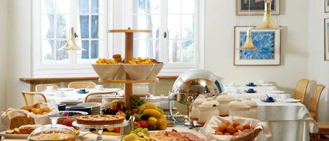 Un bufé de desayuno con diversas opciones de comida y un comedor con sillas y mesas.