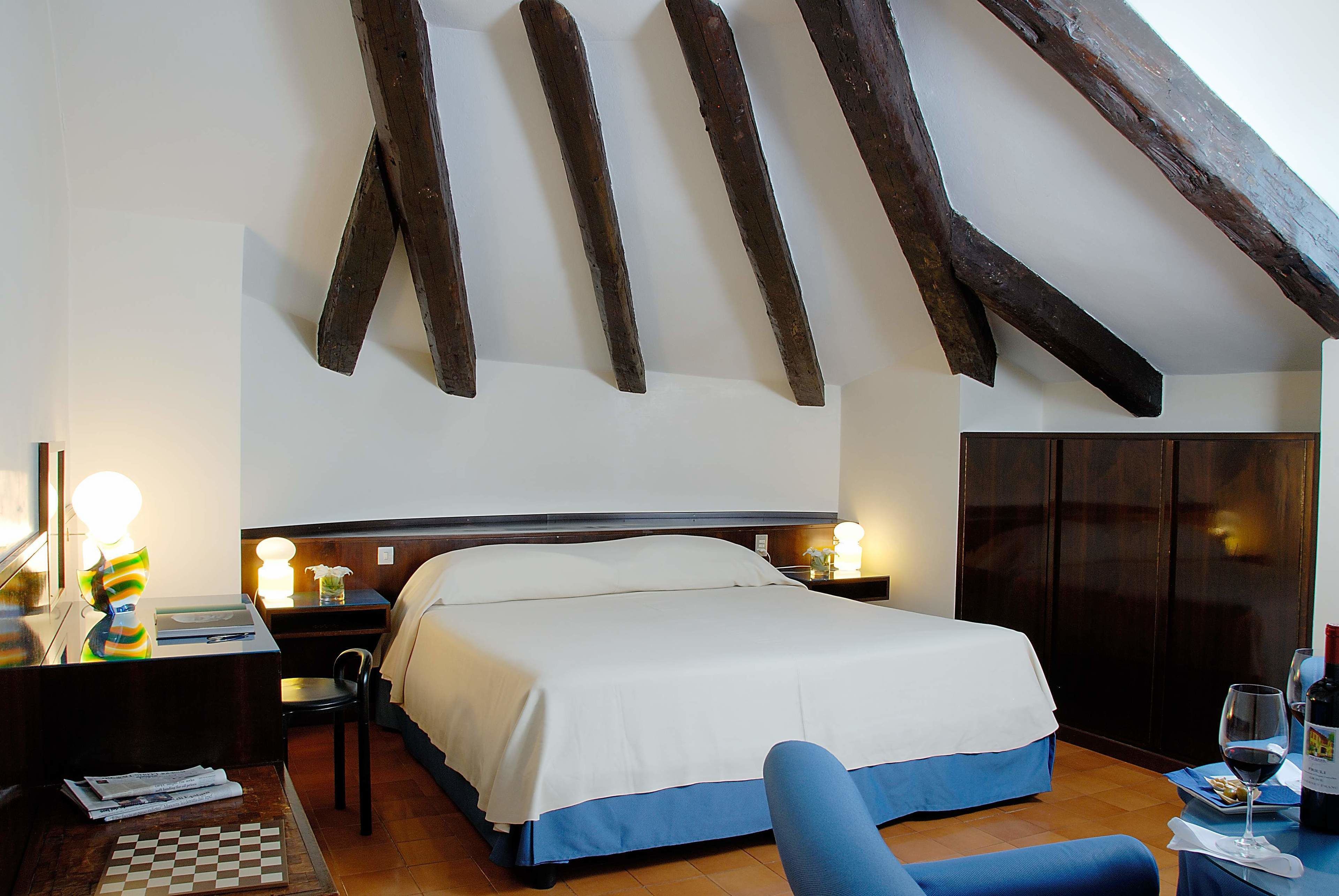 A bedroom with a bed, bedside tables, a desk, a chair, and a wardrobe.