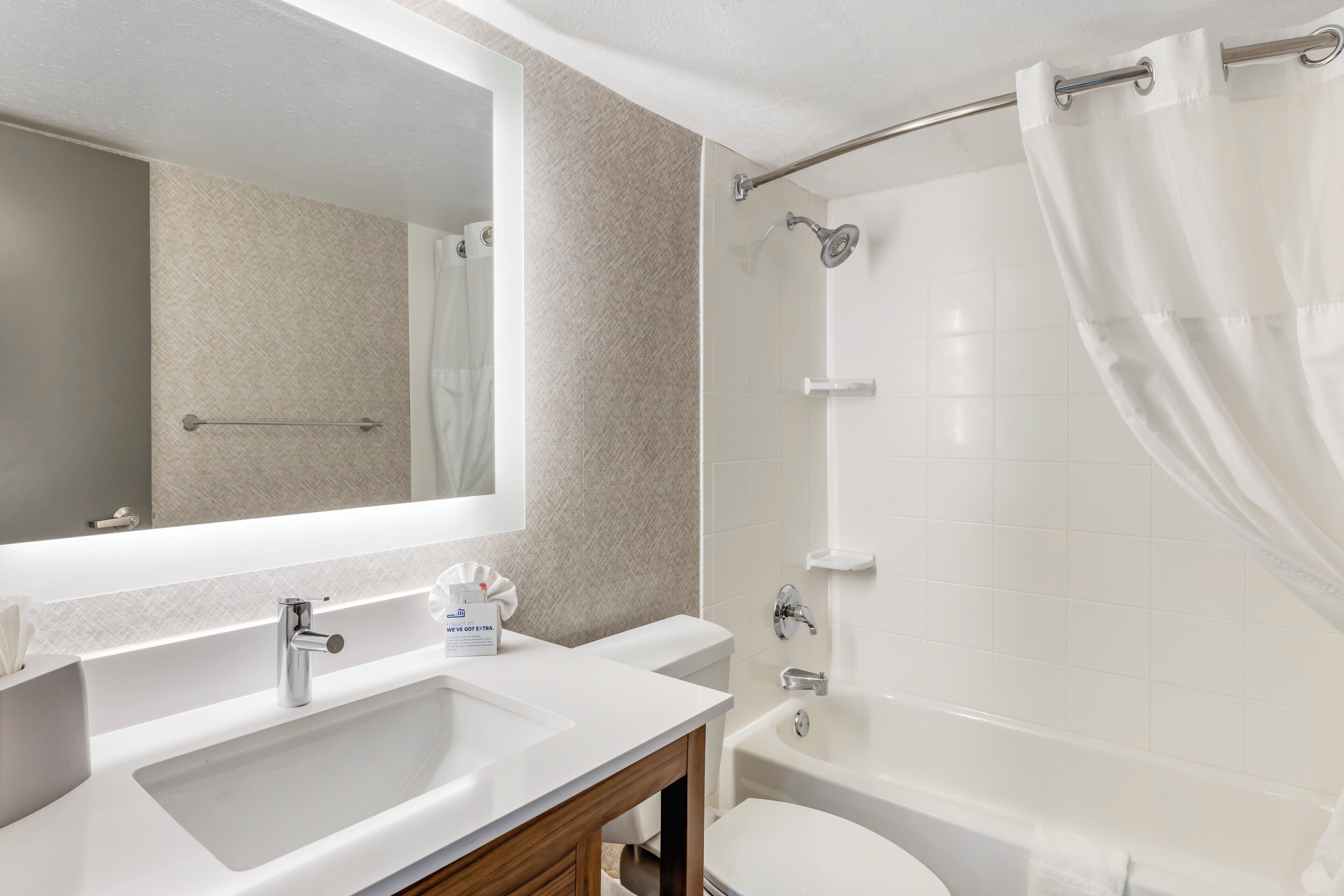 Une salle de bain moderne avec un grand miroir, un lavabo, des toilettes et un espace douche.