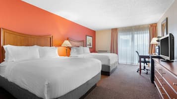 A hotel room with two beds, a desk with a television, and a window with curtains.