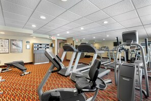 Un gimnasio con cintas de correr, elípticas y equipo de pesas.