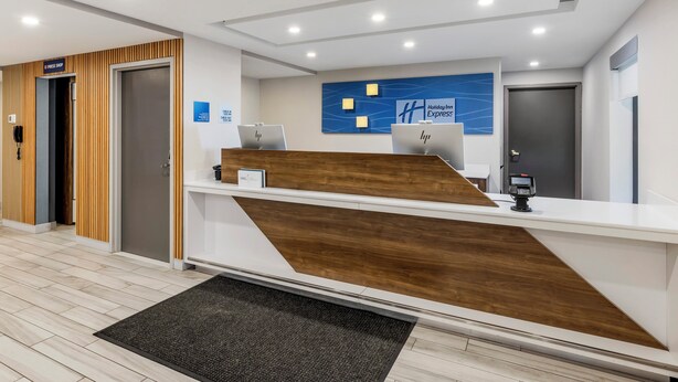 Ein Empfangsbereich mit Holzelementen, einem Holiday Inn Express Schild und einer kleinen Schreibtischlampe.
